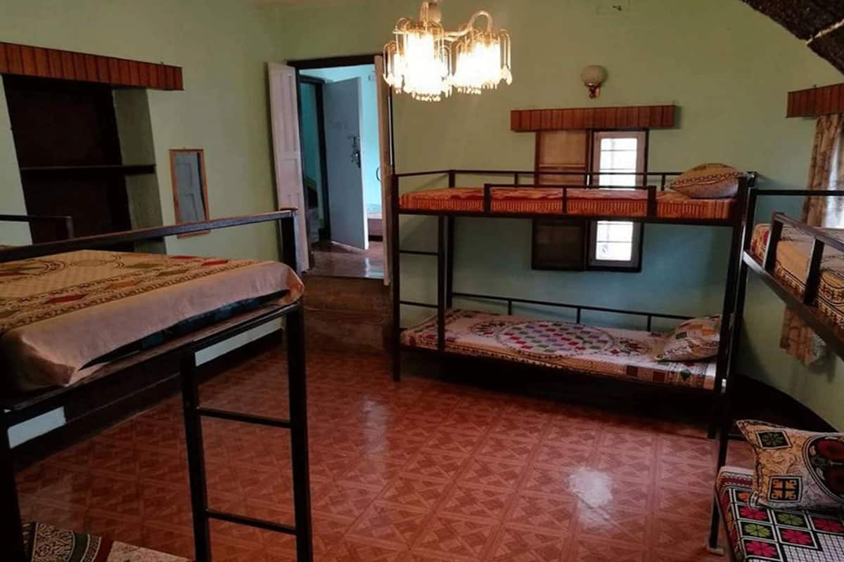 A room with bunk beds, a chandelier, and a door leading to another room.