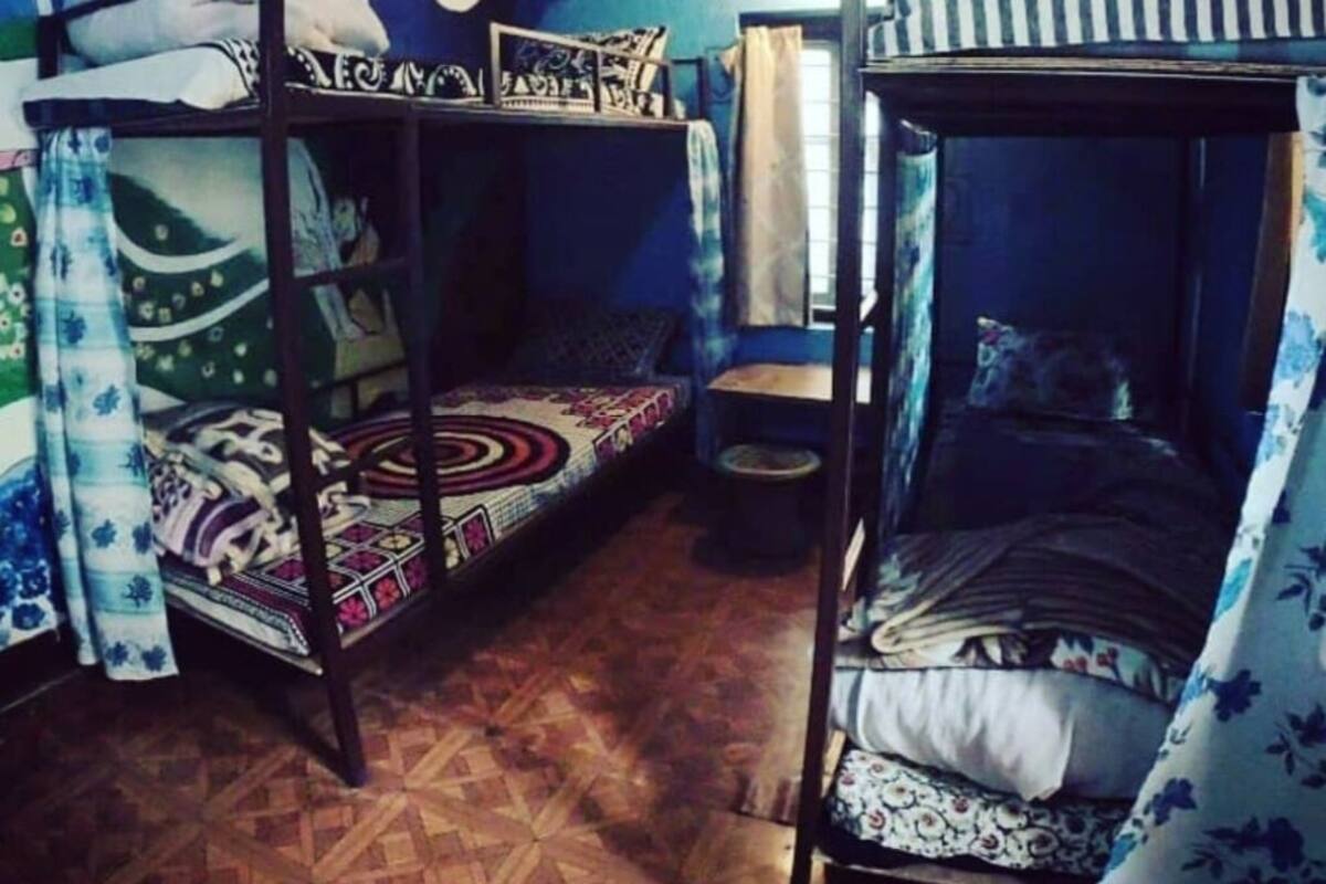 A dormitory room with bunk beds, a small table, and a wall with a mural.