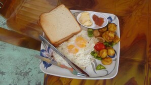 A plate with toast, fried eggs, roasted potatoes, and a small bowl of sauce. - The Nepali Hive (Kathmandu)