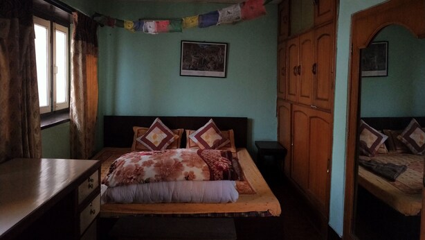 A bedroom with a bed, a desk, a wardrobe, and a window. - The Nepali Hive (Kathmandu)