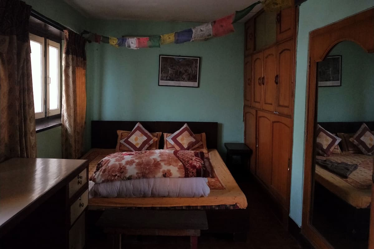 A bedroom with a bed, a desk, a wardrobe, and a window.