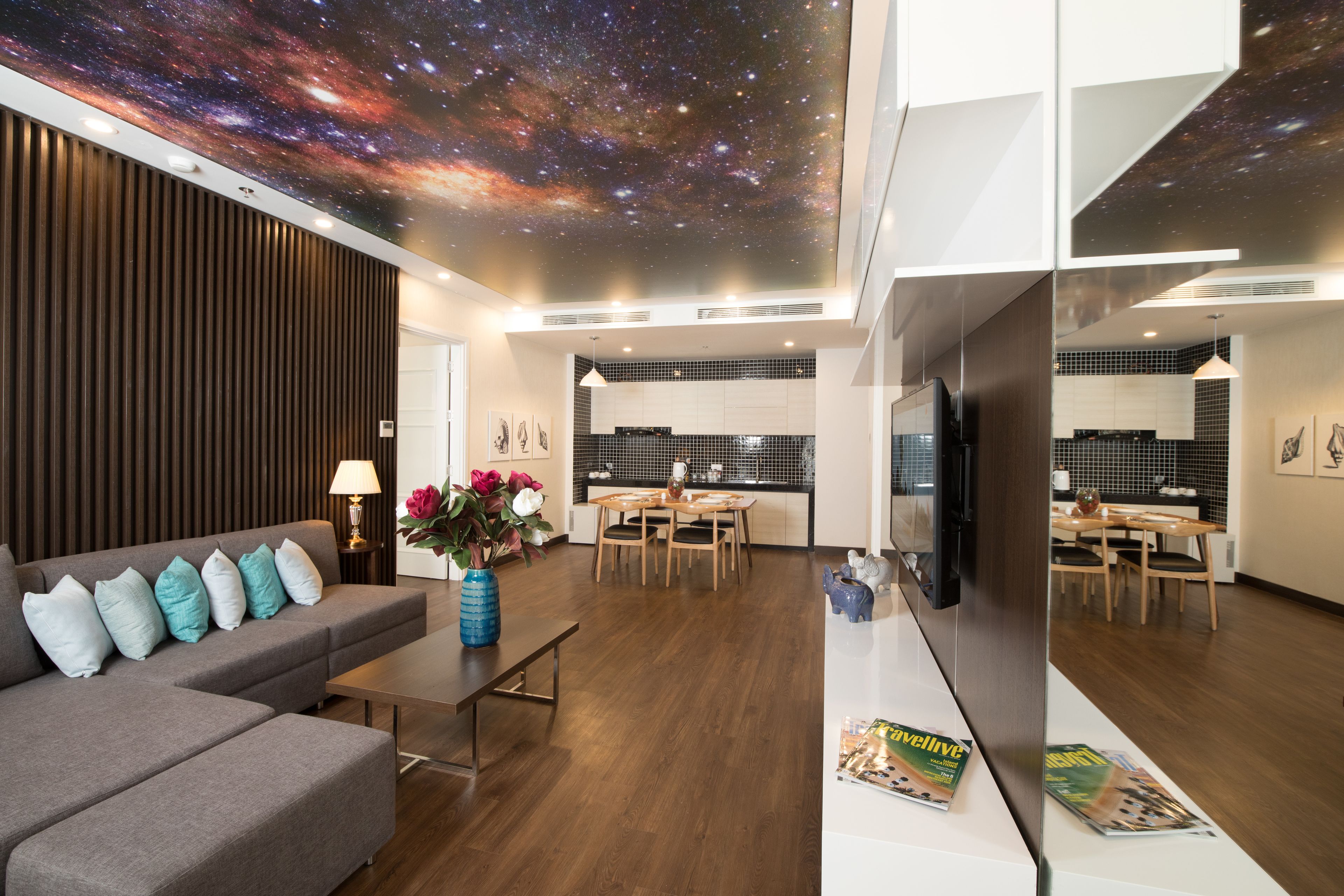 A modern living room with a sofa, a coffee table, and a dining area with a kitchen in the background.
