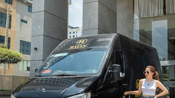 A black van with a luggage trolley parked in front of a building with a large space-themed mural on the wall.