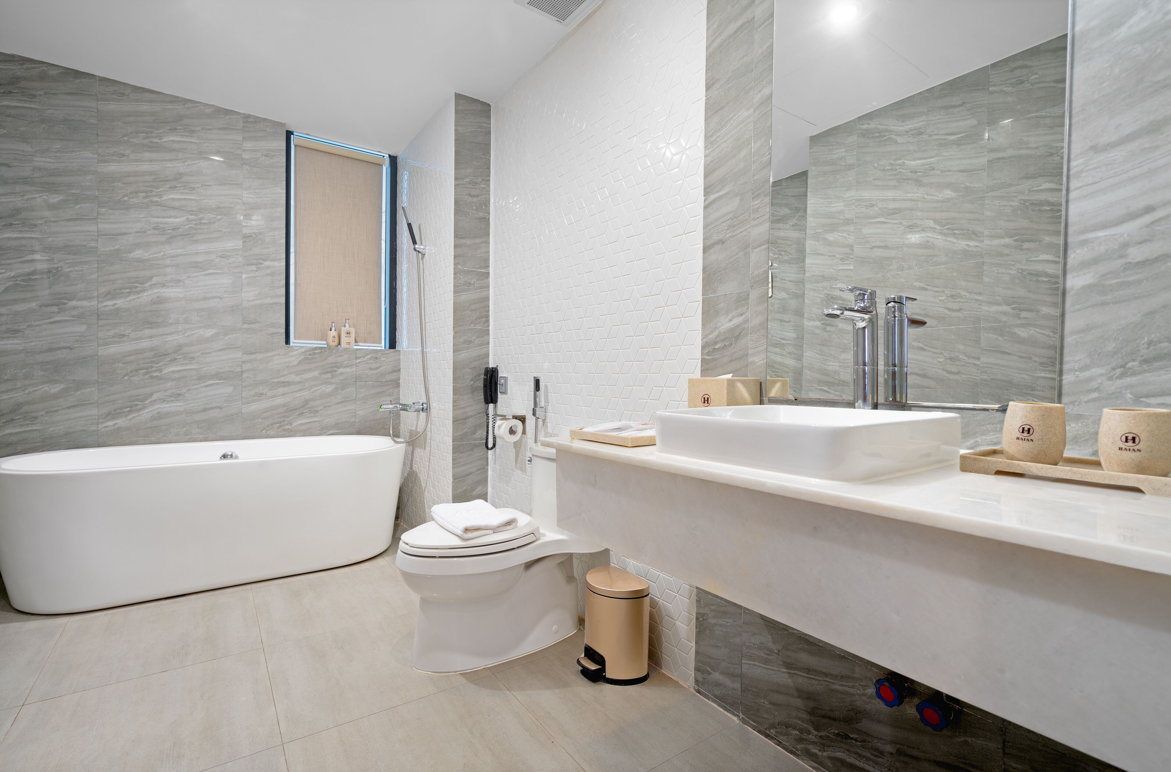 Een moderne badkamer met een bad, toilet en wastafel.