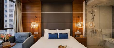 Une chambre d’hôtel moderne dotée d’un grand lit, d’un coin salon, d’une douche et offrant une vue sur la ville.