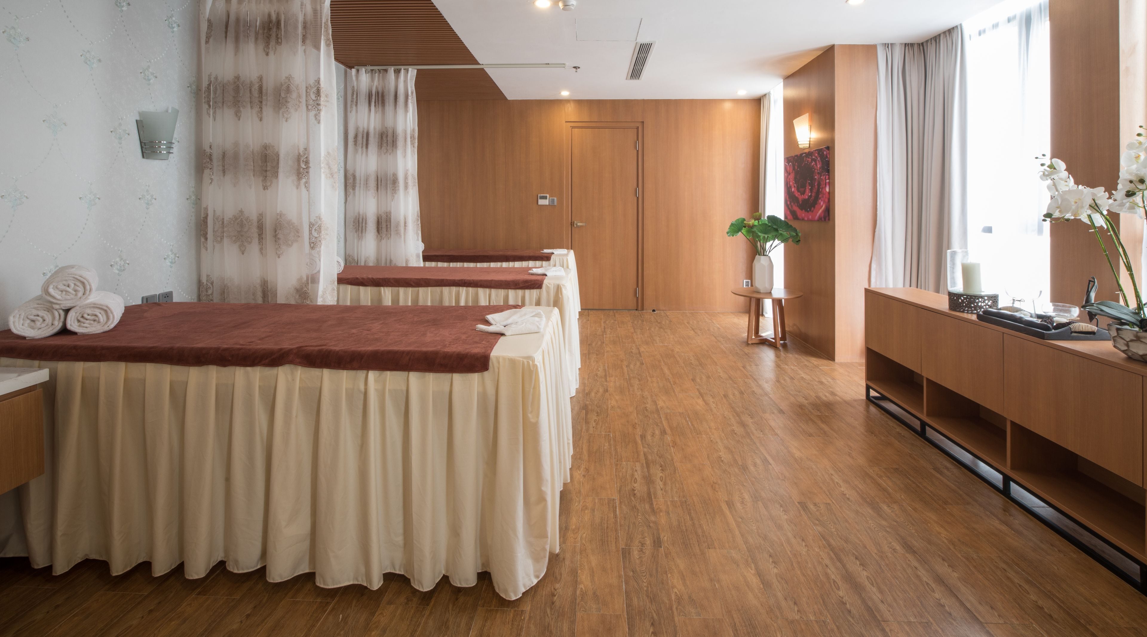 Un cuarto de spa con pisos de madera, un mostrador de recepción y una camilla para masajes con una manta roja.