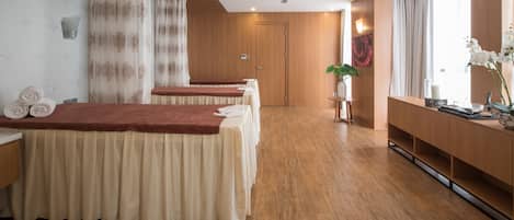 Un cuarto de spa con pisos de madera, un mostrador de recepción y una camilla para masajes con una manta roja.