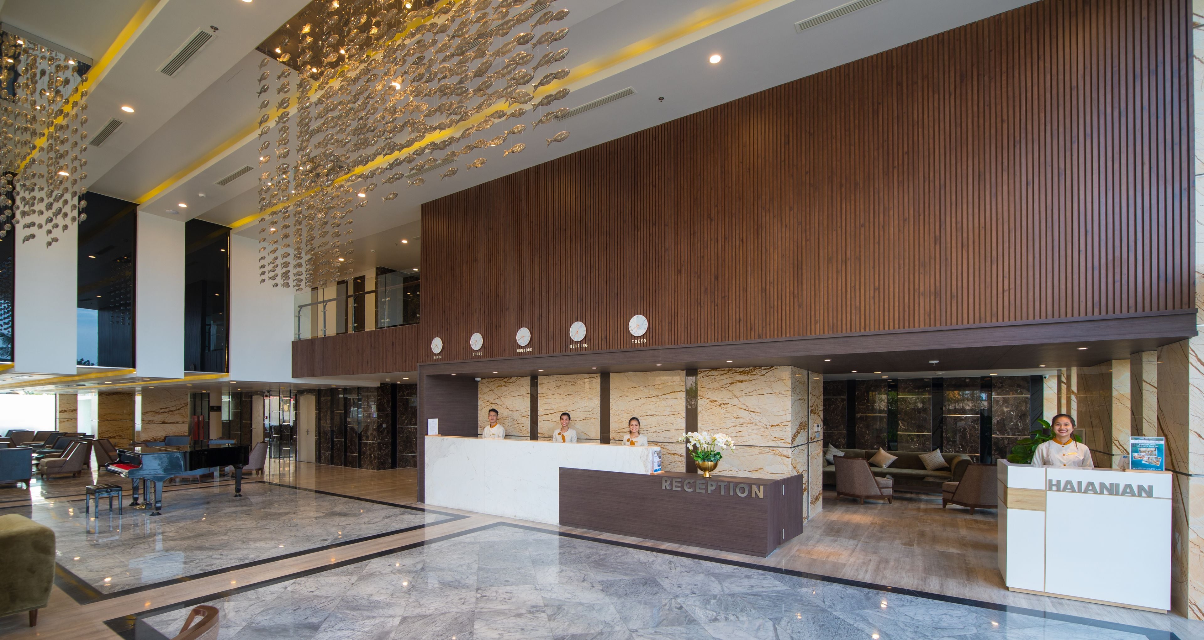A modern hotel reception area with a marble floor, wooden paneling, and a reception desk labeled "HAIANIAN".