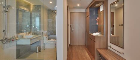 Un baño moderno con cabina de ducha de vidrio, tocador con espejo y banco de madera.