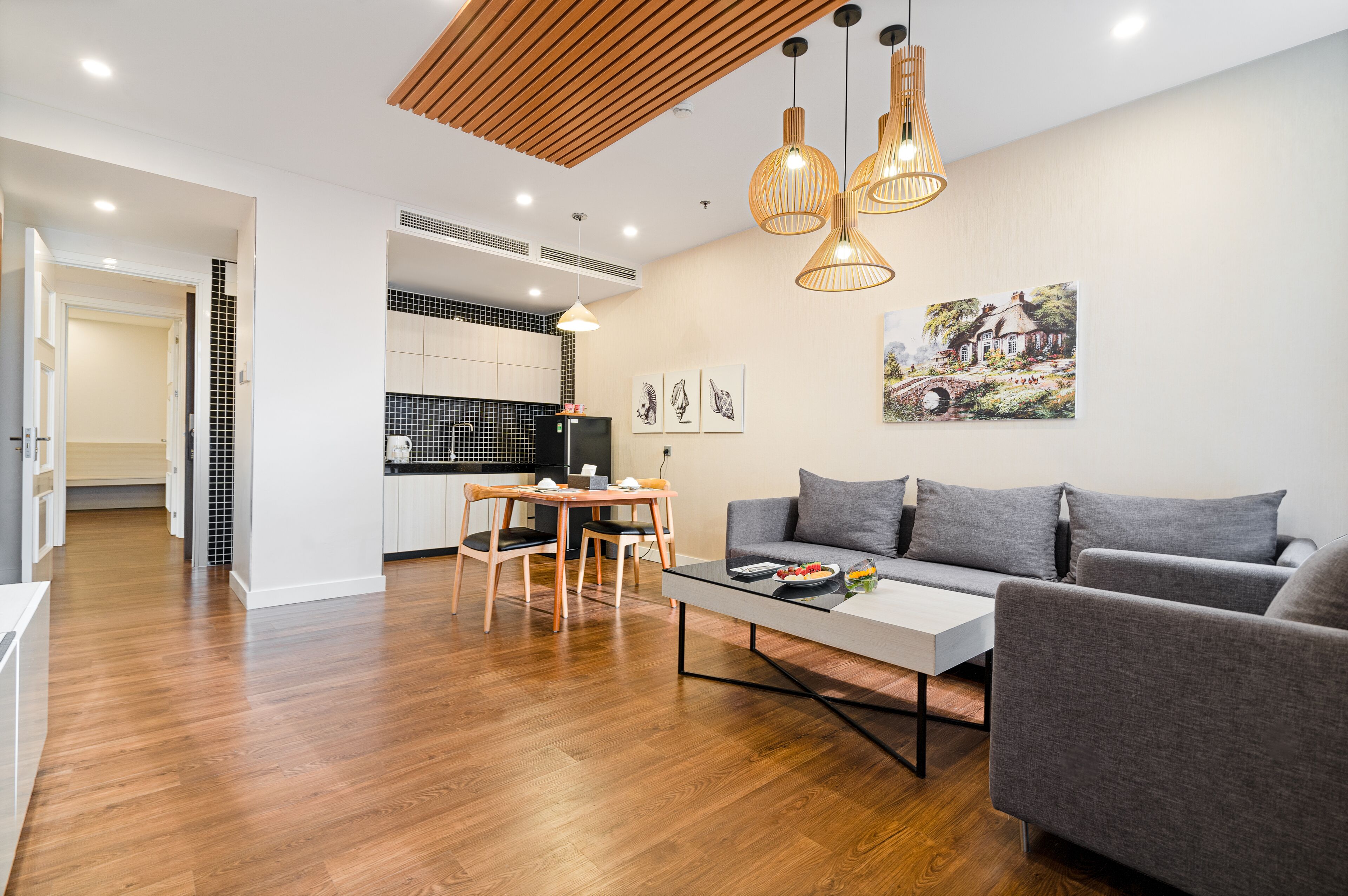 A modern living room with a grey sofa, wooden dining table, and pendant lights.