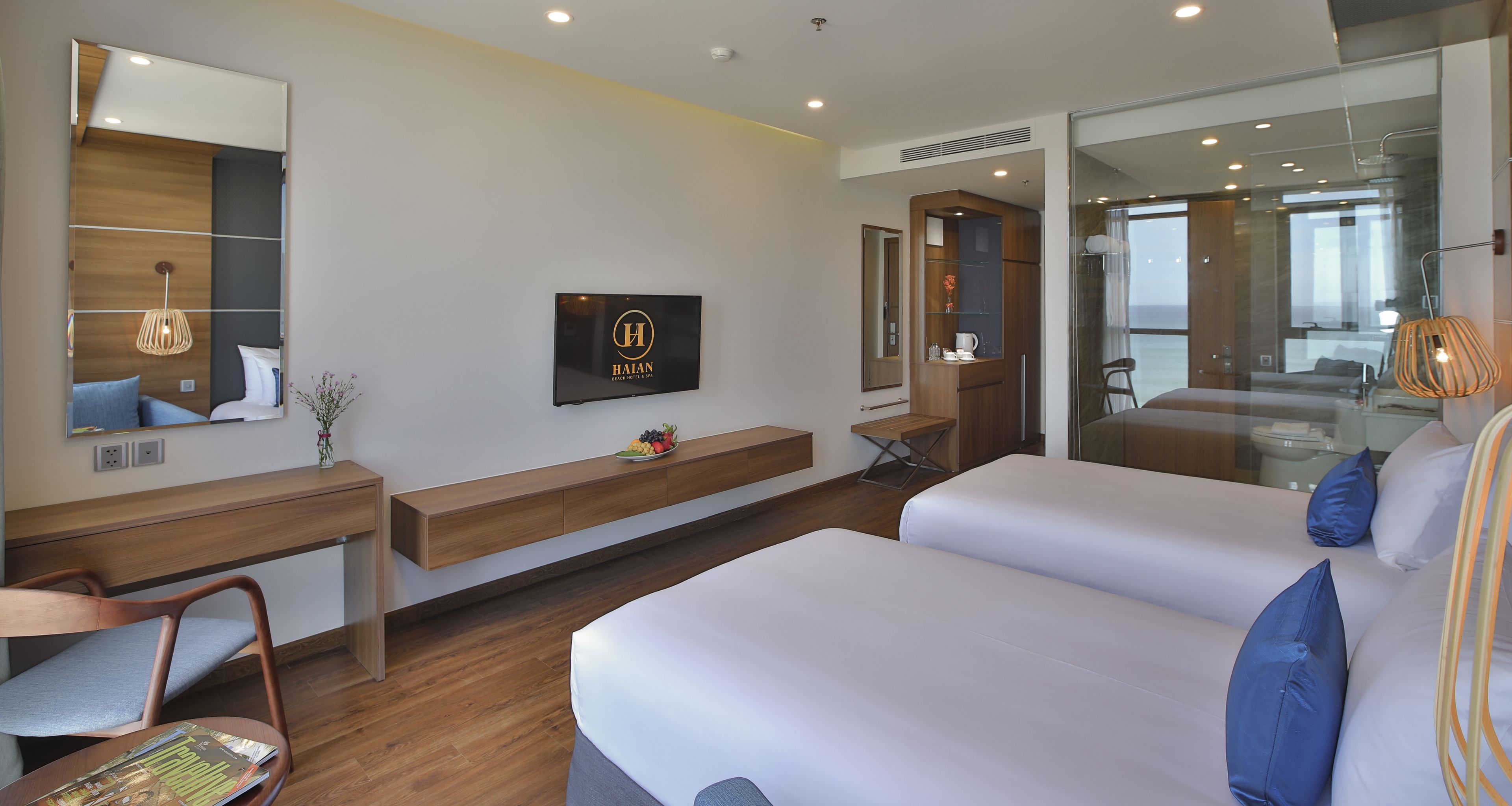 A modern hotel room with a bed, a desk, a chair, a TV, and a large window.