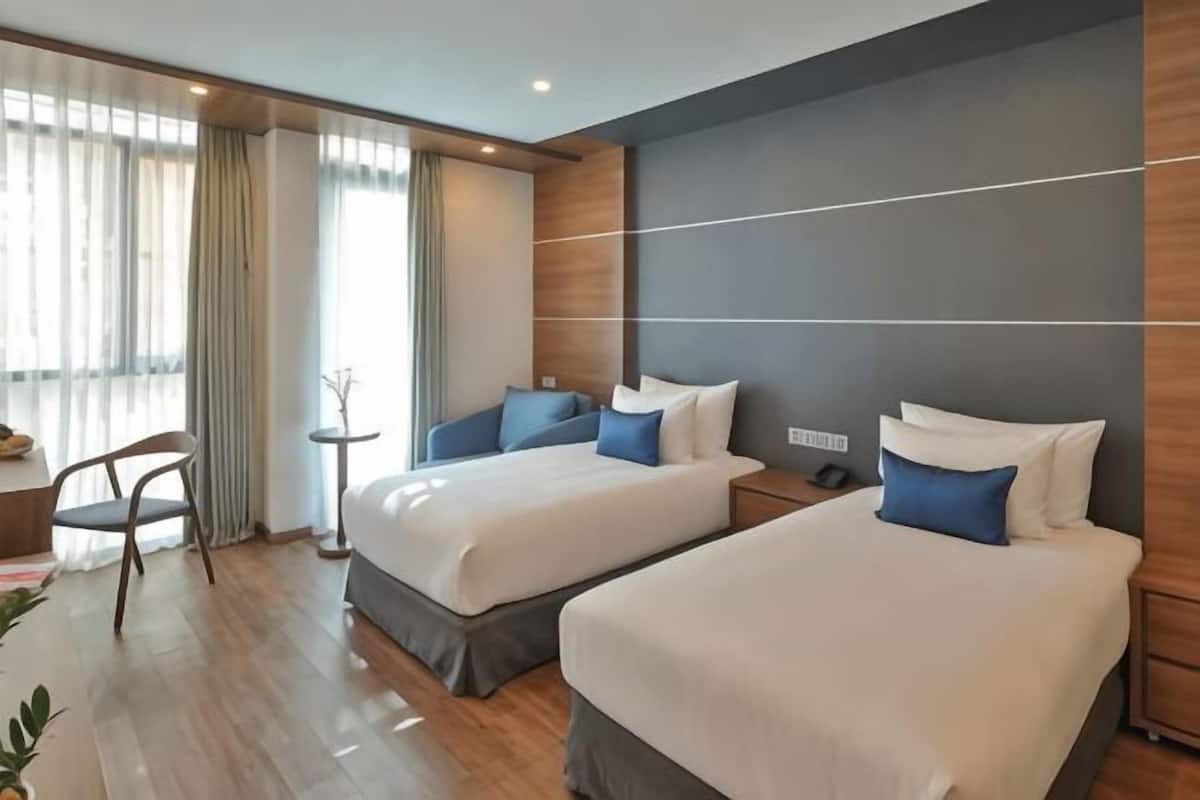 A hotel room with two beds, a desk, and a chair.