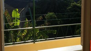 A window with a view of a balcony, plants, and a building in the background. - Bed and Breakfast Il Melangolo (Sant'Antioco)