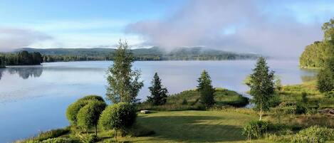 A serene lakeside landscape with a clear view of the lake, surrounded by lush greenery and trees.