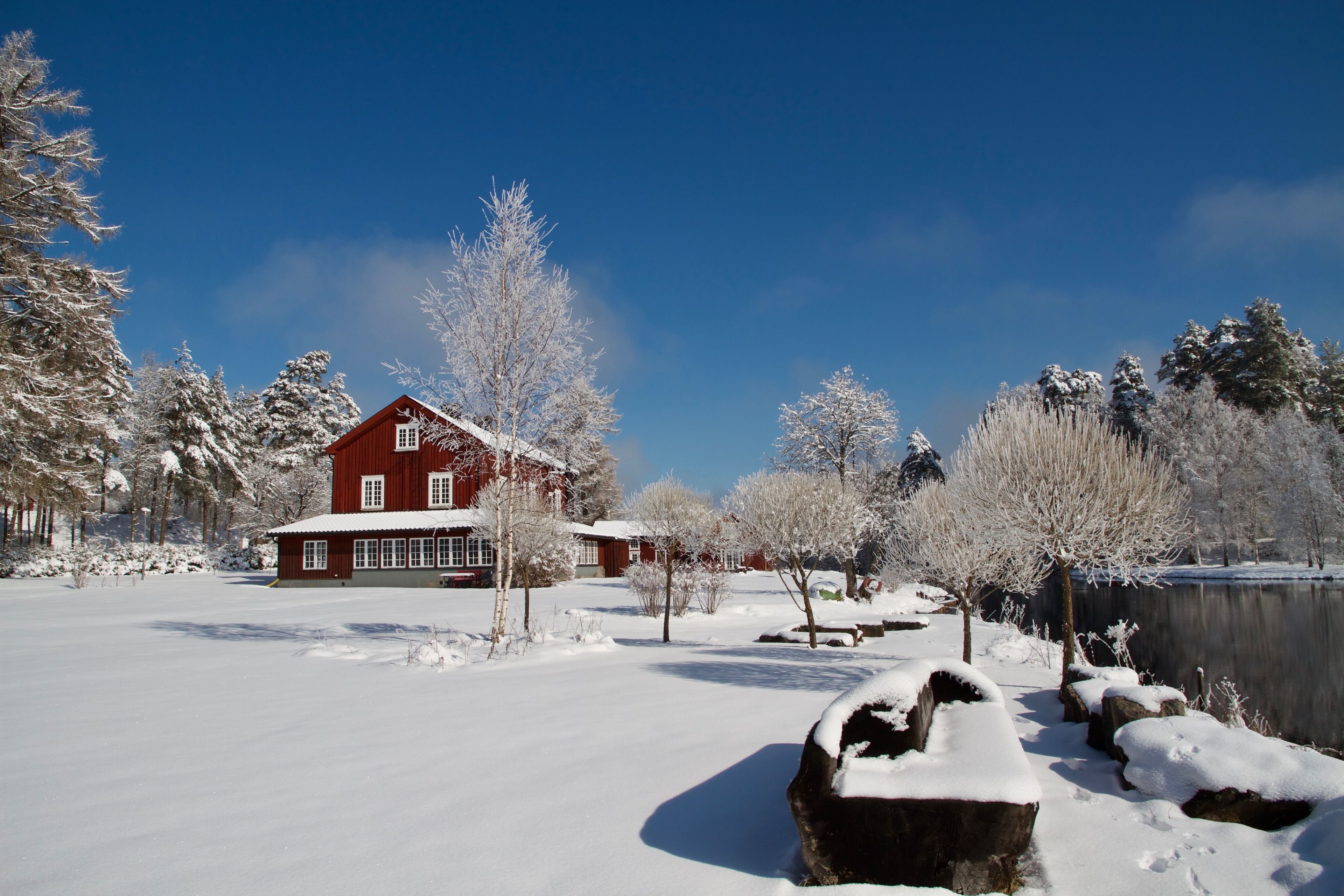 A red barn with a snow-covered landscape and trees.