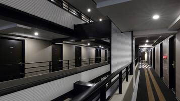 A modern hotel corridor with multiple doors, a check-in counter, and a staircase.
