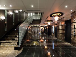 A modern hotel lobby with a central staircase, marble flooring, and contemporary lighting fixtures.