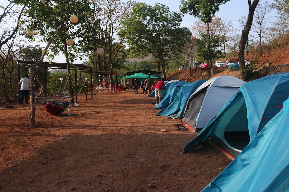 Un terrain de camping avec plusieurs tentes, un hamac et un espace de repos abrité.