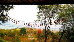 Un cartel que dice "SECRET LAKE VIEW" con el logo de un campamento, rodeado de árboles y un paisaje natural.