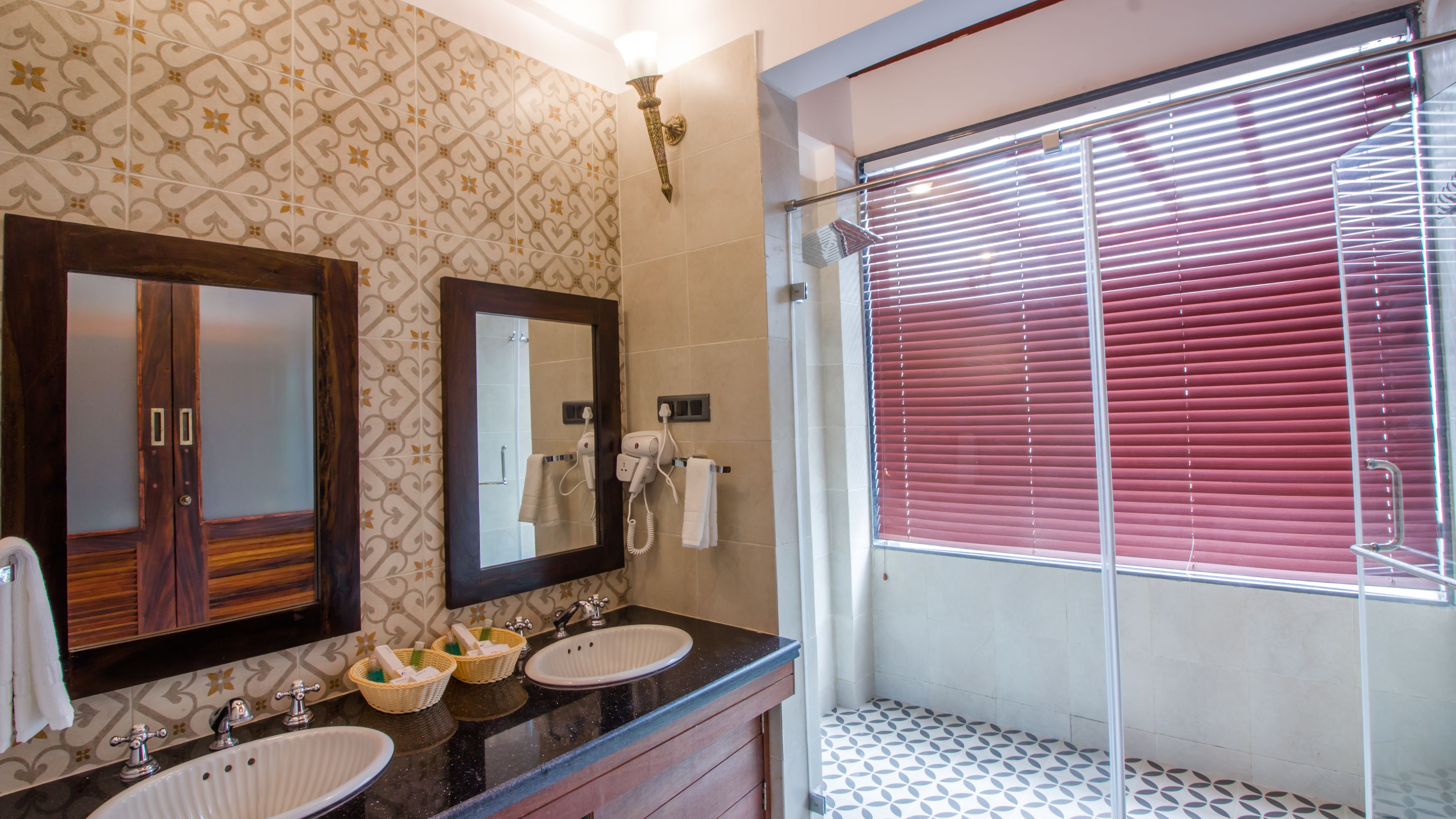 Un baño con dos lavamanos, un espejo y una ducha con persianas rojas.