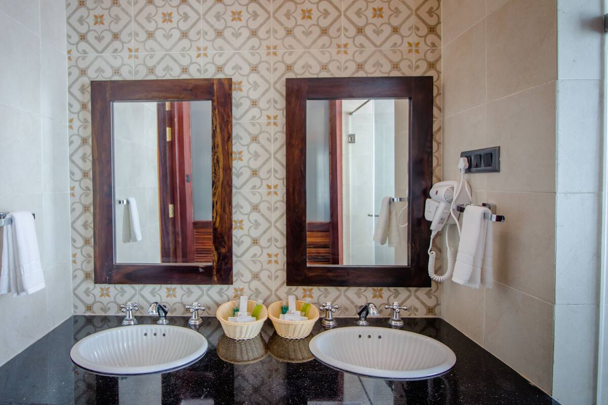 A bathroom with two sinks, a mirror, a towel rack, and a hairdryer.