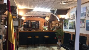 A bar area with a counter, stools, and a decorative vase. - El Castillo (Alcala de Guadaira)