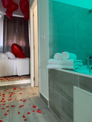 Una habitación de hotel con cama, baño con bañera y ducha.