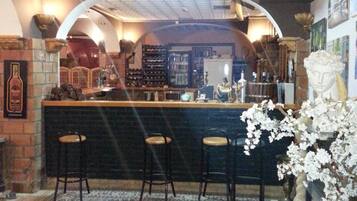 A bar area with a counter, three stools, a patterned rug, and a decorative plant.