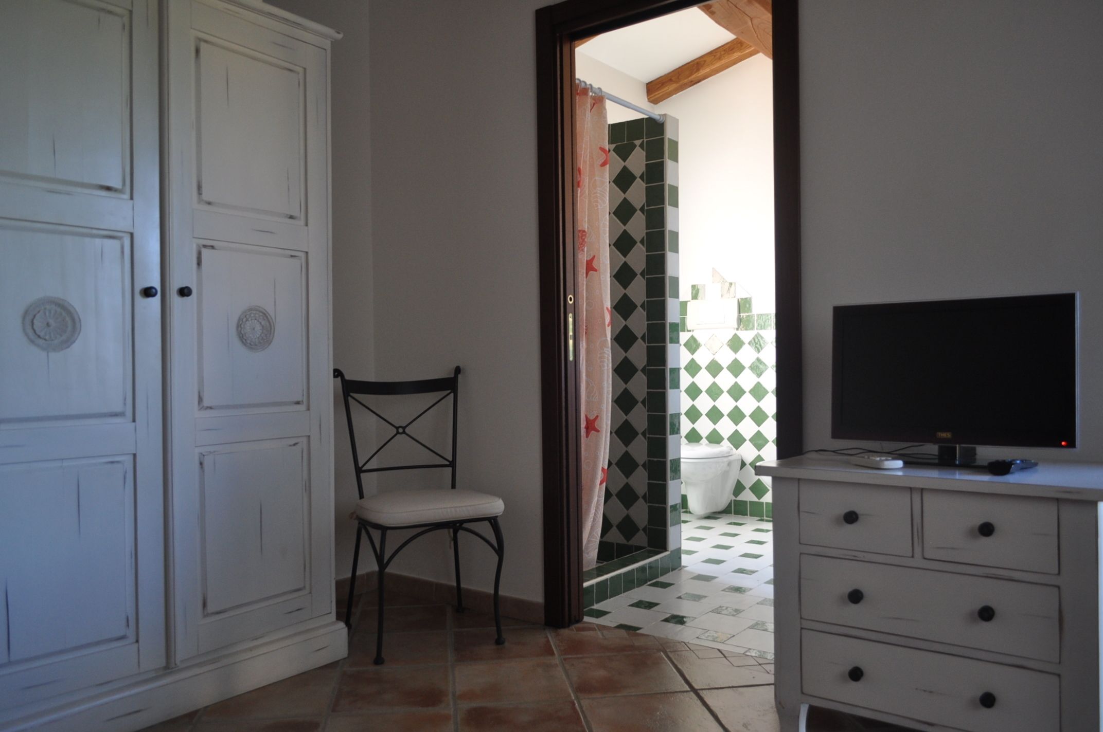 Una habitación con una televisión sobre un aparador, una silla y un armario.