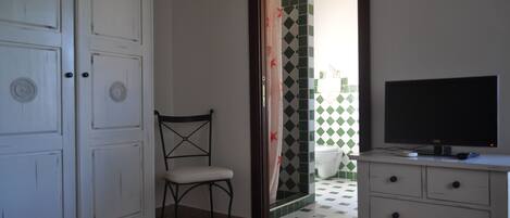 Una habitación con una televisión sobre un aparador, una silla y un armario.