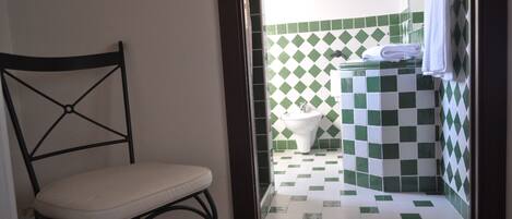 Un baño con piso a cuadros, un inodoro y una silla.