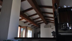 Eine Küche mit Holzbalken, einer Kaffeemaschine und einem Fenster mit Vorhängen.