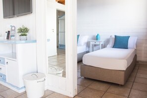 Habitación de hotel con cama, mesitas de noche, escritorio, silla, cesto de basura y planta en maceta.