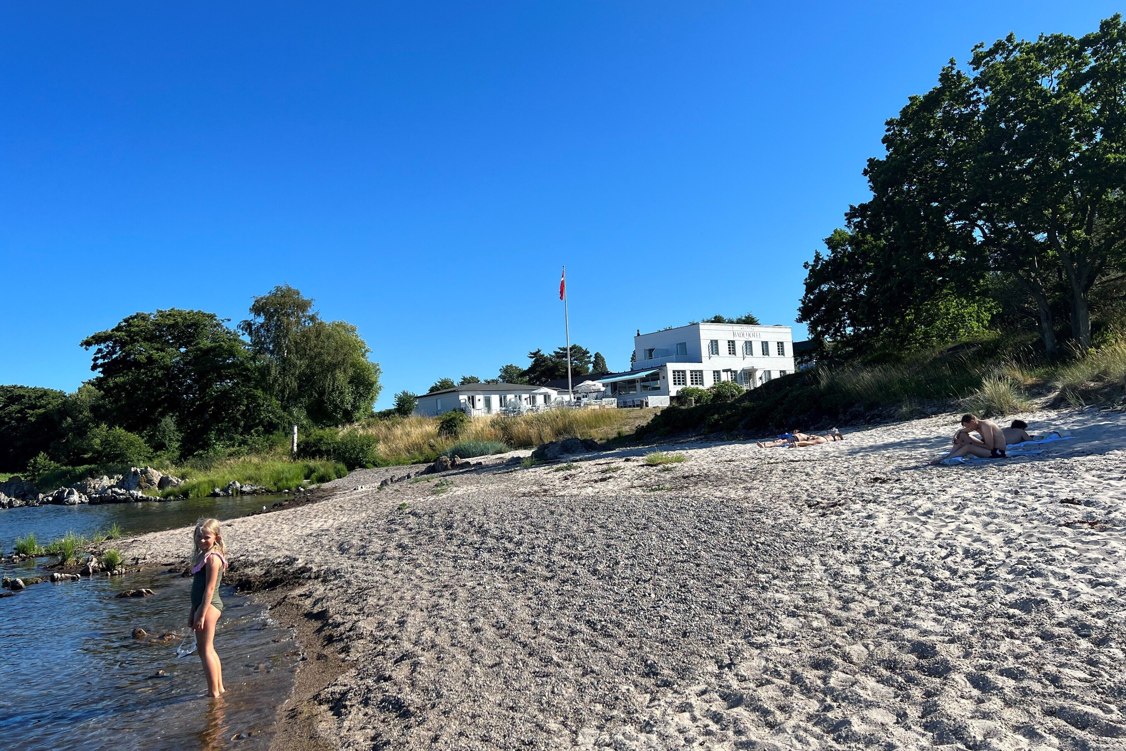 Una playa con una casa al fondo.