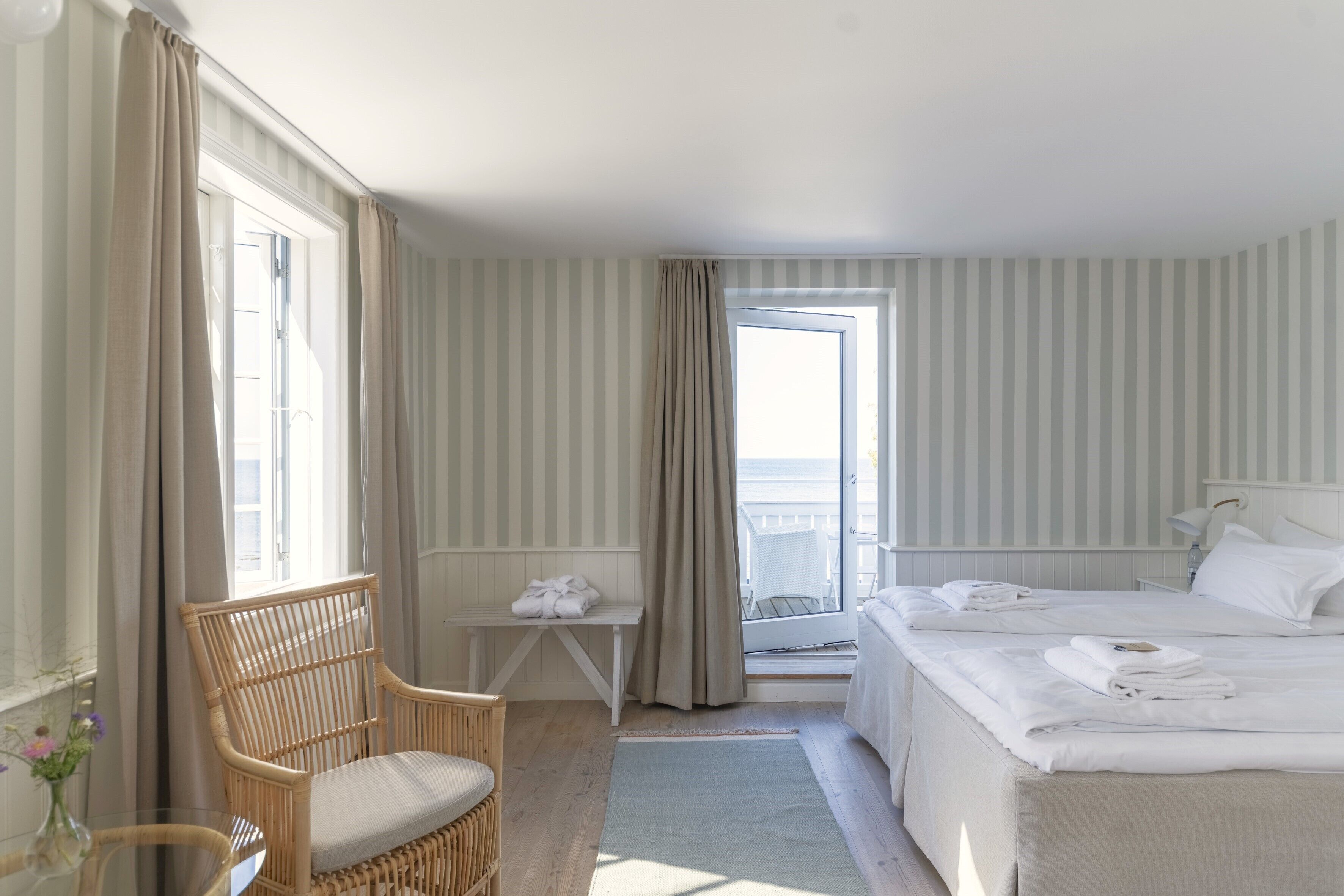 Ein Hotelzimmer mit Bett, Sessel, kleinem Tisch und Blick ins Freie.