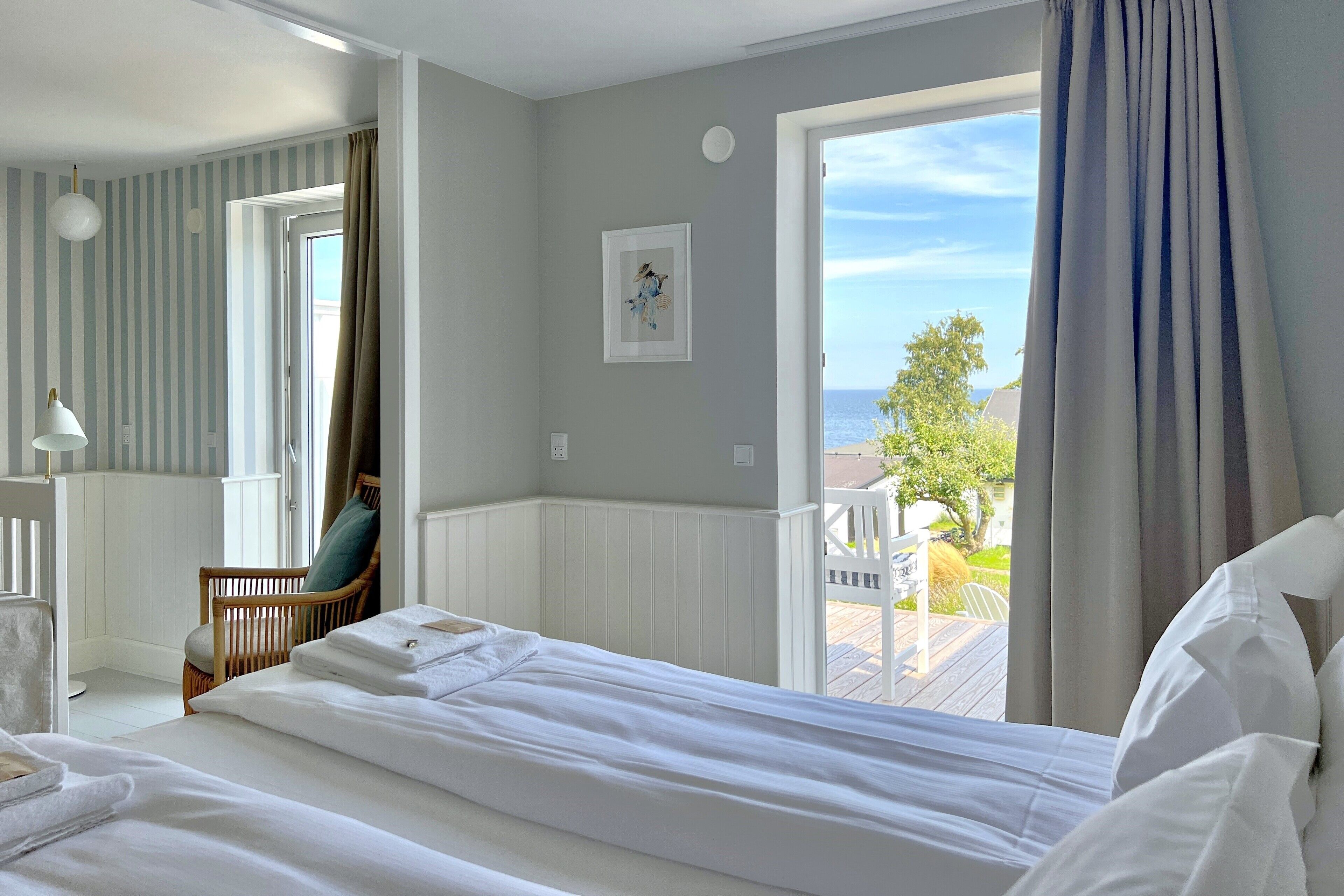 A hotel room with a bed, a chair, a window with curtains, and a view of the outdoors.