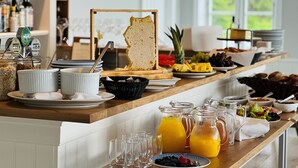 A breakfast buffet with various food items, including fruits, pastries, and beverages. - Melsted Badehotel  (Gudhjem)