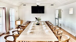 A long wooden table with chairs, a flat-screen TV on the wall, and a whiteboard. - Melsted Badehotel  (Gudhjem)
