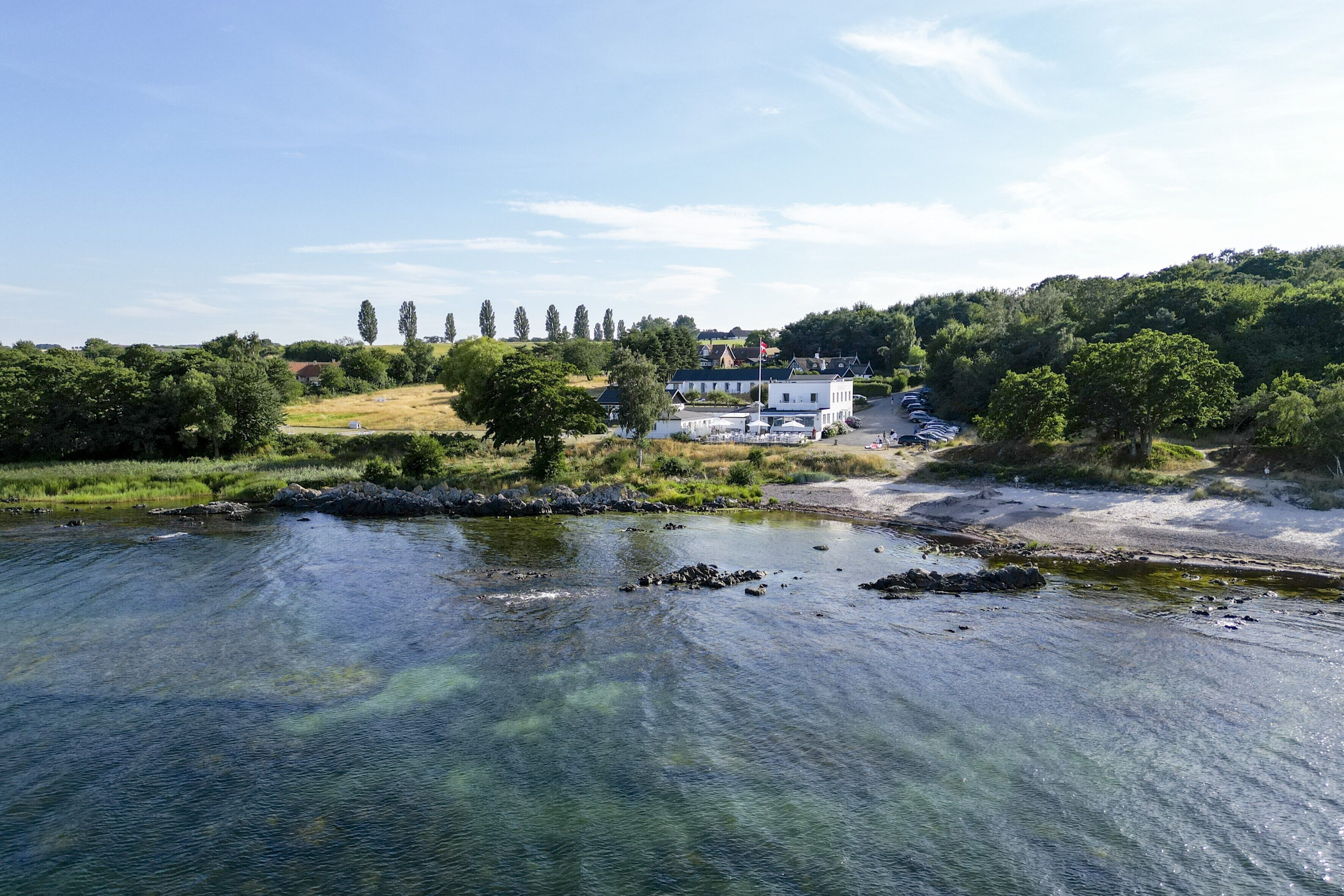 A riverside view with a building, trees, and a clear sky.