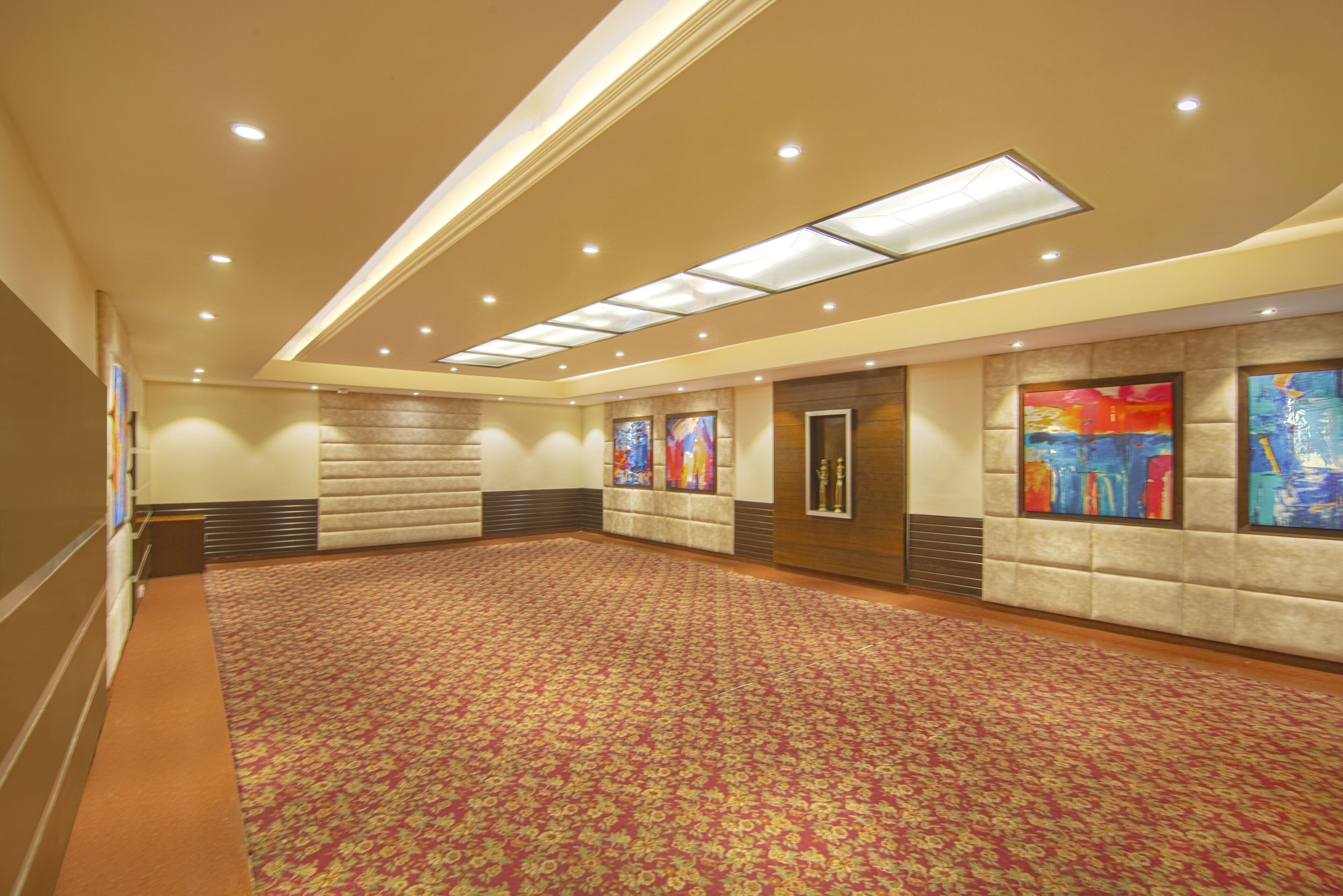 A spacious conference room with a patterned carpet, recessed lighting, and artwork on the walls.