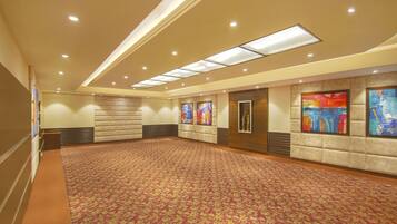 A spacious conference room with a patterned carpet, recessed lighting, and artwork on the walls.