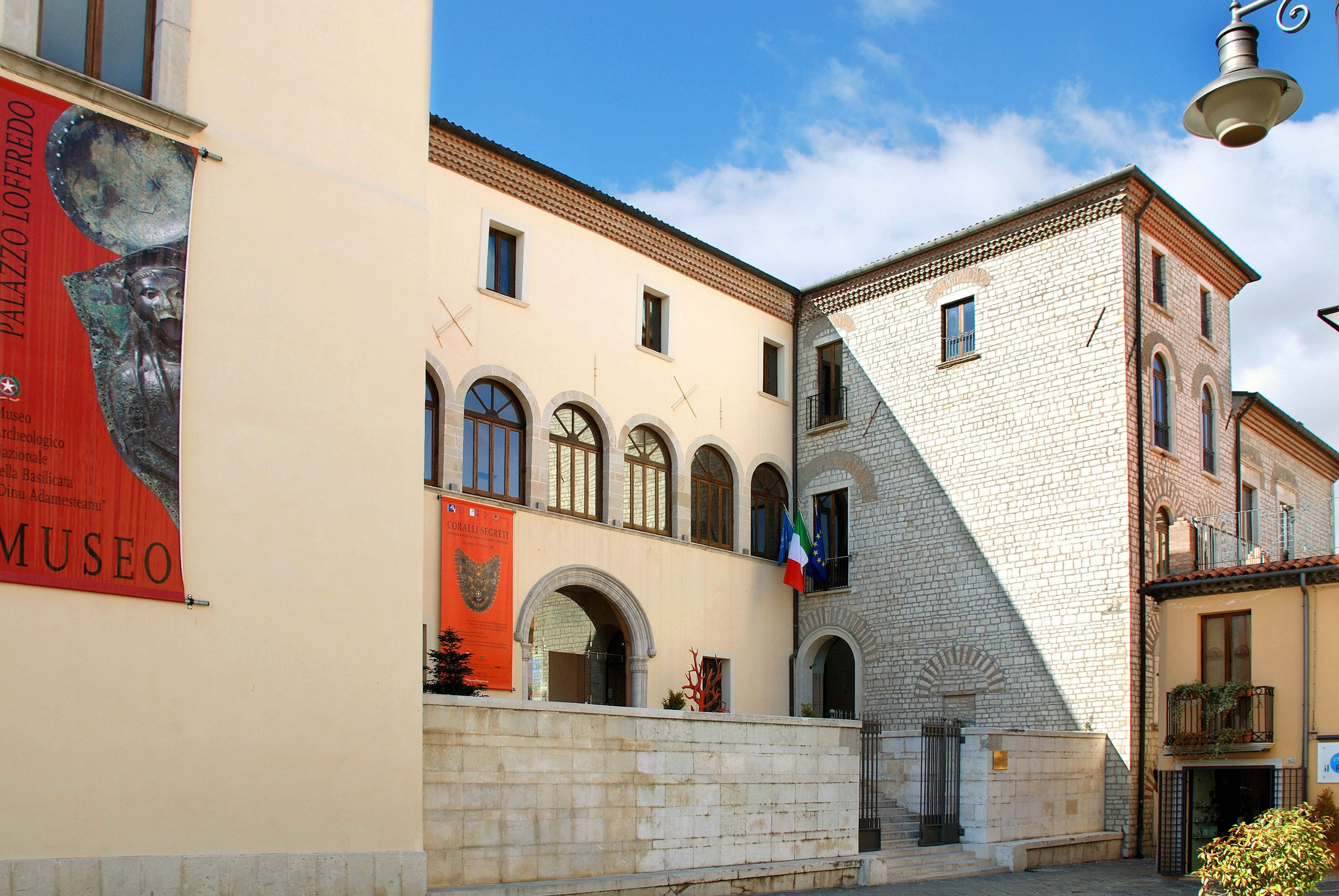 A building with a sign for Museo Palazzio Lofredo, featuring a stone facade and arched windows.