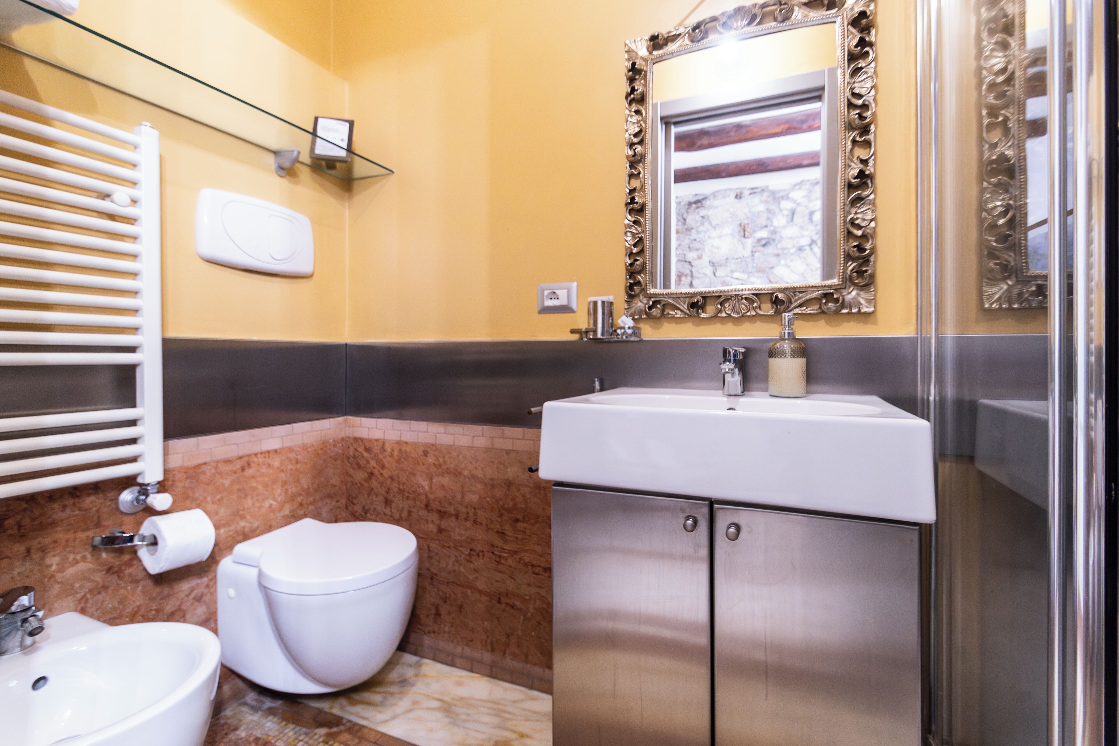 Ein modernes Badezimmer mit einem мраморной Waschbecken, Toilette und einer Duschkabine aus Glas.