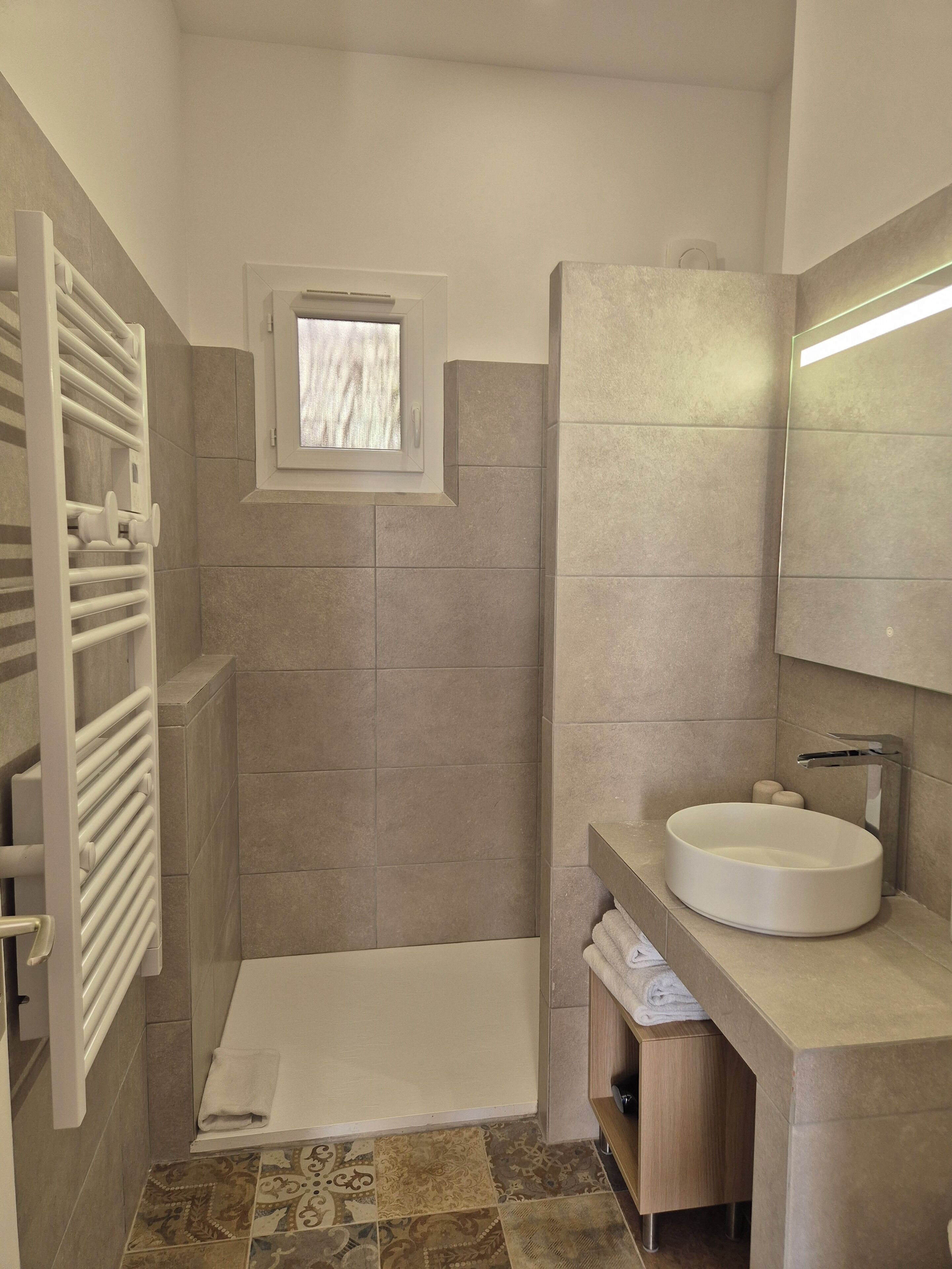 Une salle de bain moderne dotée d’une douche à l’italienne, d’un lavabo intégré et d’un porte-serviettes.