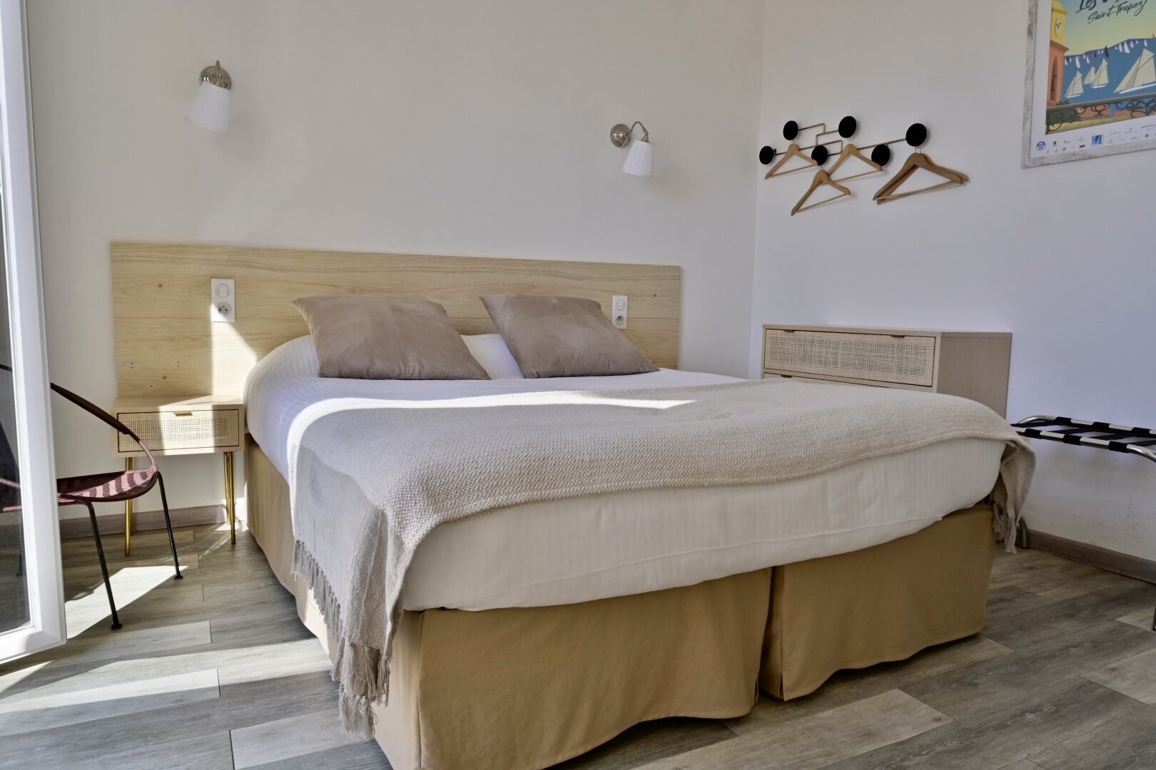 A bedroom with a bed, bedside tables, a chair, and wall-mounted light fixtures.