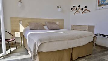 A bedroom with a bed, bedside tables, a chair, and wall-mounted light fixtures.