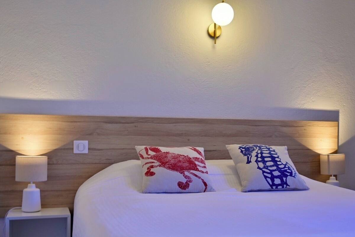A neatly made bed with two pillows, a wooden headboard, and bedside lamps.