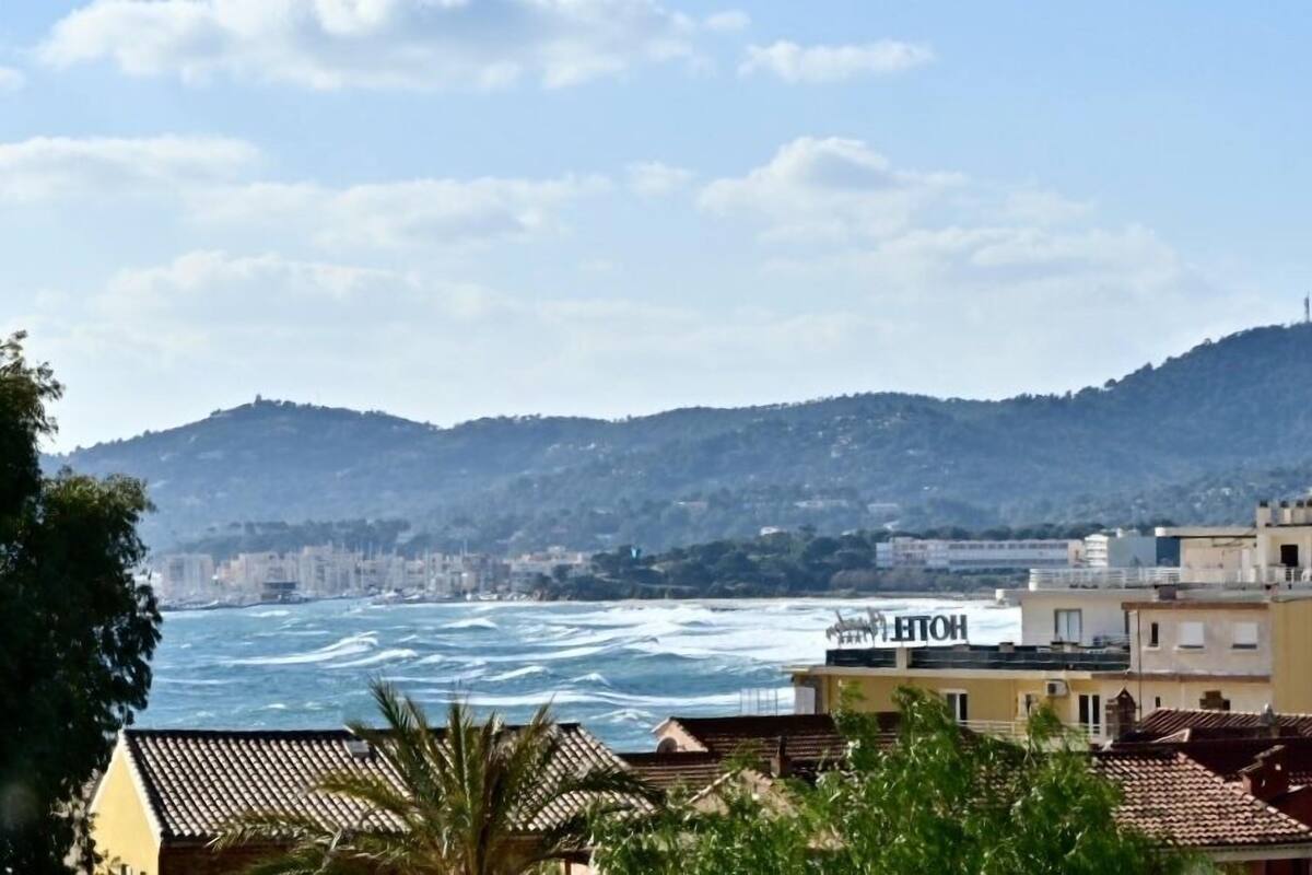 A coastal view with a hotel named "HOTEL" in the foreground, a cityscape in the background, and a hilly terrain.