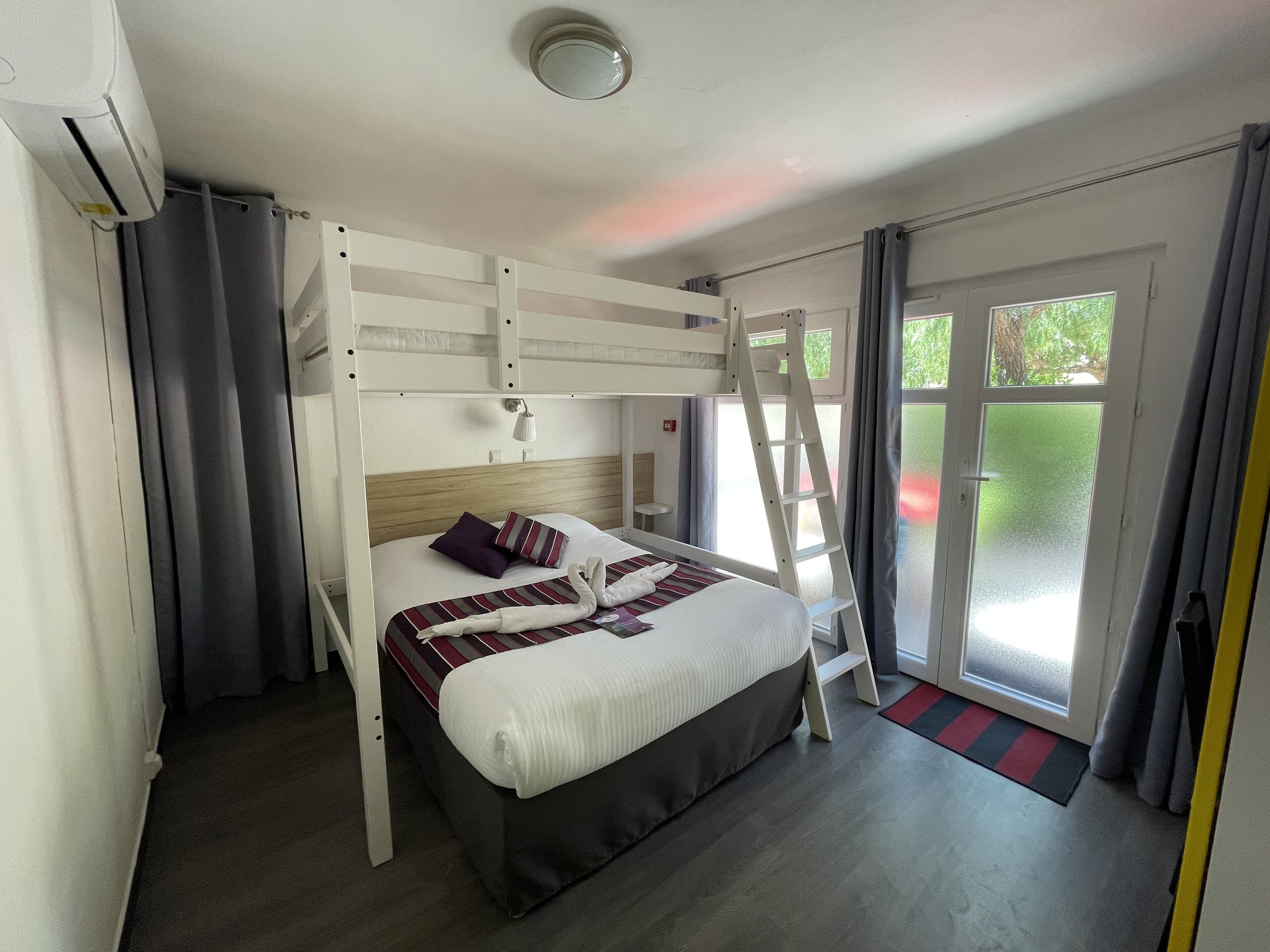 Un letto a castello con una scala, un comodino e una finestra con tende.