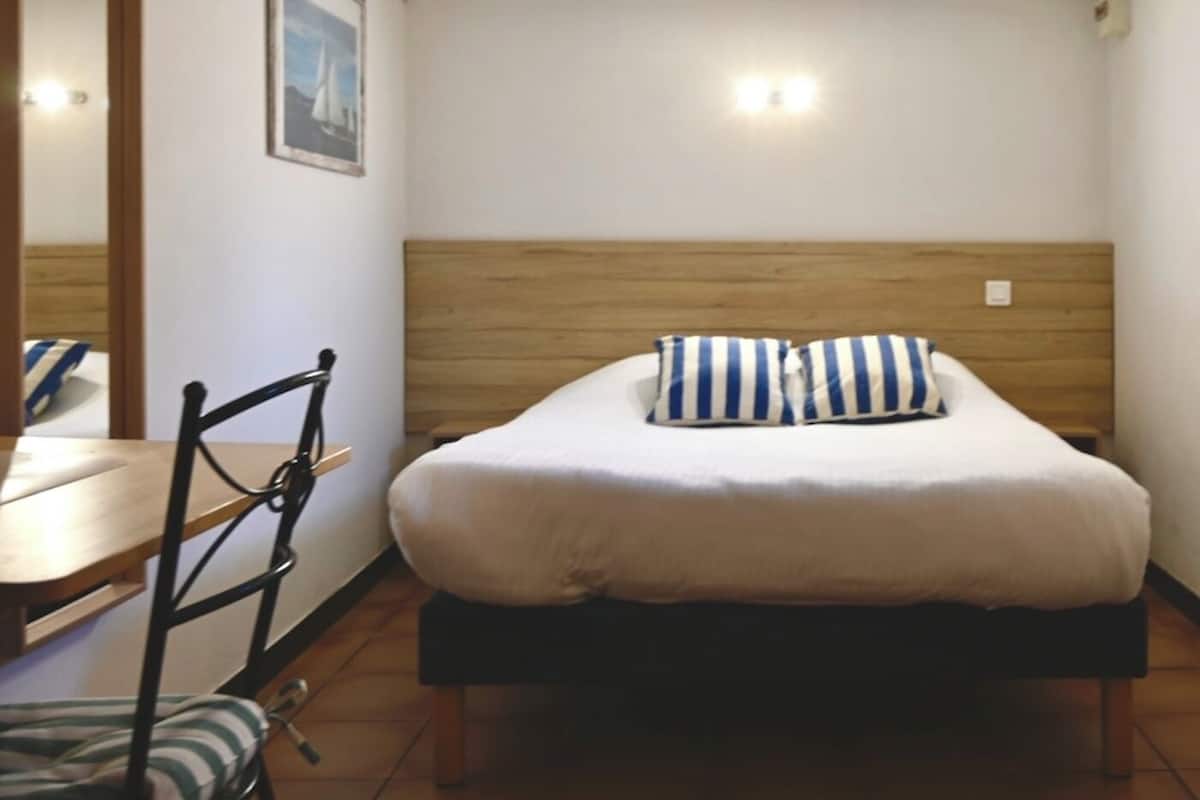 A single bed with a wooden headboard, a striped pillow, and a small bedside table.
